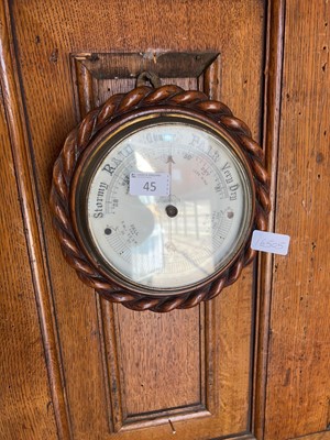 Lot 45 - A circular aneroid barometer in an oak case