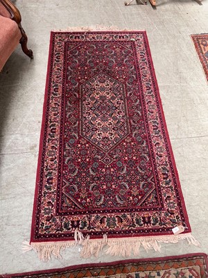 Lot 73 - An eastern style red ground hand woven wool...