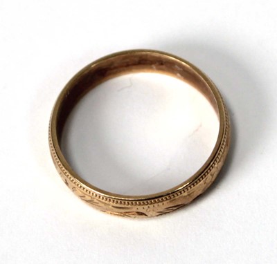 Lot 533 - A 9ct yellow gold scroll engraved wedding band,...