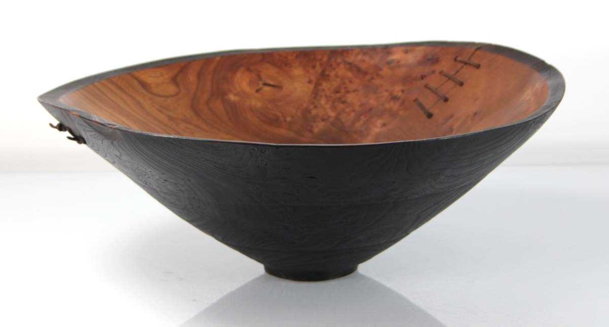 Lot 89 - A turned wooden bowl with leather straps by...