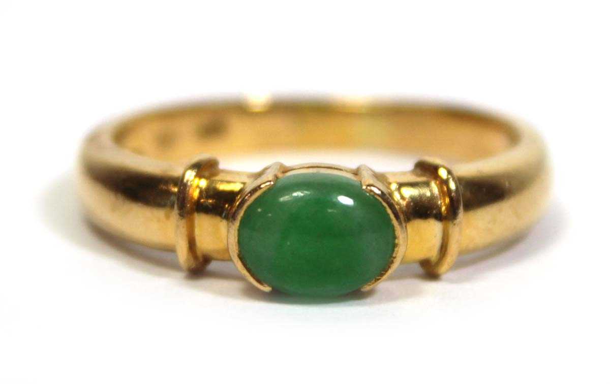 Lot 671 - A yellow metal ring set oval cabochon green...