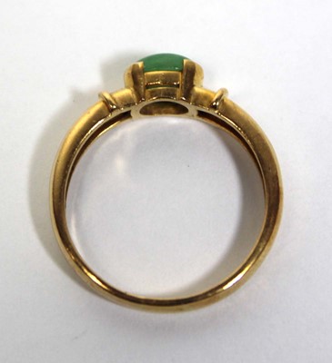Lot 671 - A yellow metal ring set oval cabochon green...