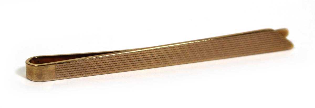 Lot 707 - A 9ct yellow gold engine turned tie clip,...