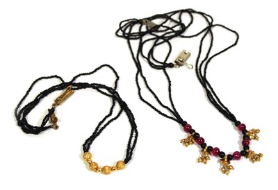 Lot 712 - A triple strand black bead necklace suspending...