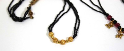 Lot 712 - A triple strand black bead necklace suspending...