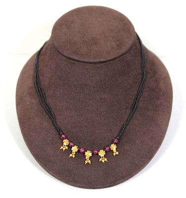 Lot 712 - A triple strand black bead necklace suspending...