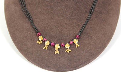 Lot 712 - A triple strand black bead necklace suspending...
