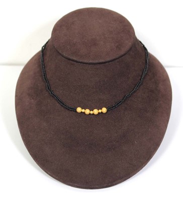 Lot 712 - A triple strand black bead necklace suspending...