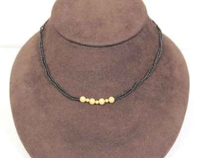 Lot 712 - A triple strand black bead necklace suspending...