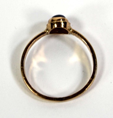Lot 759 - A yellow metal ring set cabochon sapphire in a...